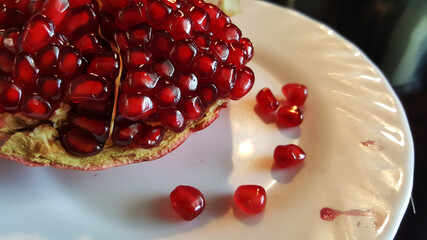 art photo of a cut pomegranate on a plate with dropped seeds close-up