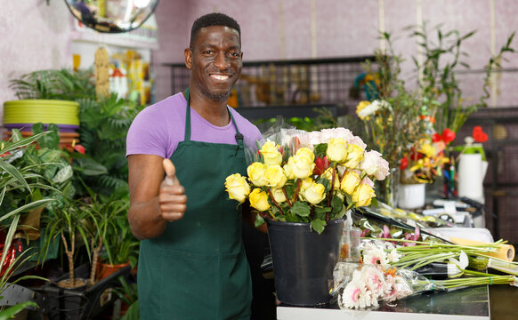 Satisfied successful African American male florist giving thumbs up at his flower shop
