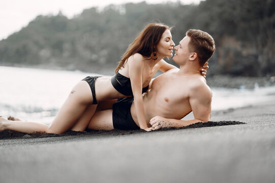 couple relaxing at a secluded private beach in Bali Indonesia. couple showing affection on a hidden beach. Couple wearing bathingsuits - Powered by Adobe