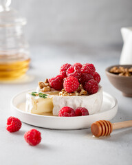 sliced camembert cheese with raspberries, honey and walnuts . White background, selective focus, 