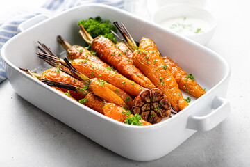 baked carrots in a white ceramic form on a light background, close-up, selective focus