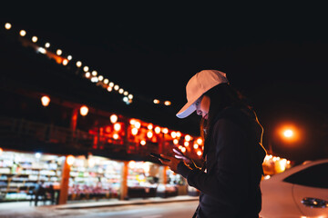 Asian adult woman using mobile phone  for call taxi at night.