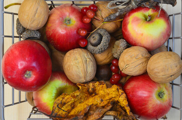basket with autumn decor, organic and healthy autumn food, apples, walnuts, fallen leaves top view, thanksgiving day concept