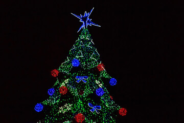 Obraz premium Decorated Christmas tree with multi-colored lights at night