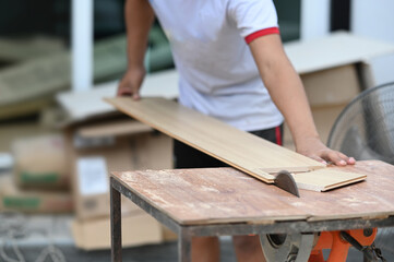 Cropped shot of carpenter cutting a piece of wood in his woodwork workshop.
