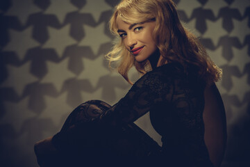 Naklejka premium Vintage portrait of pretty smiling blonde woman posing in black dress