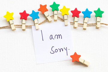 i am sorry message card handwriting with colorful wooden star clips arrangement flat lay postcard...
