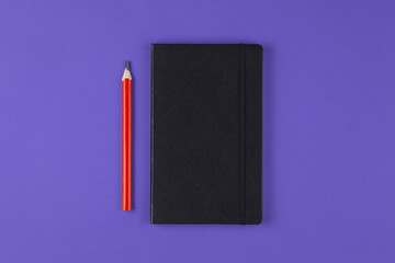 black notebook with pencil on violet background