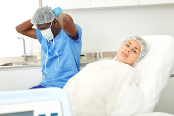 Obraz premium Female client in armchair before facial procedure in clinic of esthetic cosmetology, male on background