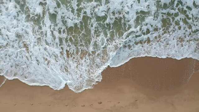 Video over an empty beautiful sandy beach and picturesque sea waves that flood the footprints in the sand, Black Sea coast, Bulgaria