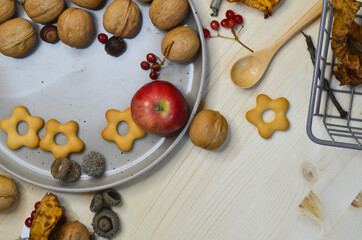 Autumn decor and decoration nuts leaves, acorns, rowan, cookies and apples on a wooden backgdrop. The concept of celebrating thanksgiving day