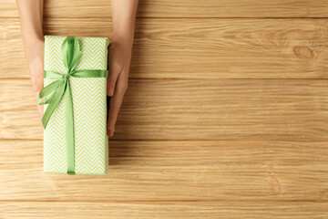 Fototapeta premium gift box in the hands on a wooden background