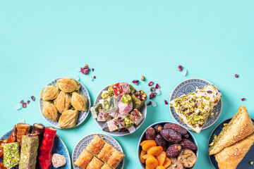 Middle Eastern sweets on blue background. Arab dessert, baklava, halva, rahat lokum, sherbet, nuts, pistachios, dates, raisins, dried apricots, churchkhela, cookies. Top view. Flat lay. Copy space