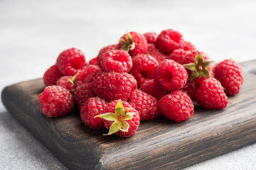 A pile of fresh juicy raspberries on a wooden Board, copy space.
