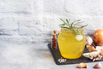 Homemade beef bone and vegetable broth with turmeric seasoning in a glass jar for storage and carrying. Healthy food with collagen and amino acids. Copy space.