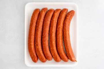 Smoked pork sausages in plastic container, close up directly from above