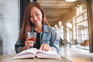 Portrait image of a young beautiful asian woman drinking coffee and reading book