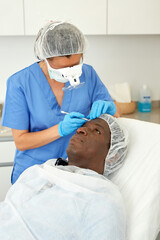 Cosmetician female in mask is preparing client for mesotherapy in beauty clinic