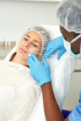 Naklejka premium Man doctor in mask making beauty injection to female client in estetic clinic