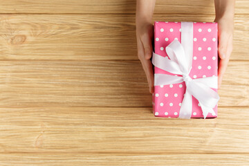 Fototapeta na wymiar gift box in the hands on a wooden background