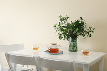 White kitchen table with tea and plant in bright room