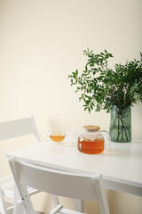 White kitchen table with tea and plant in bright room