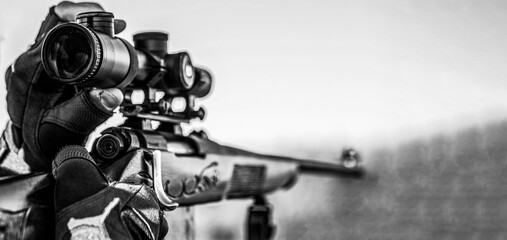 Hunting period. Male with a gun. Close up. Hunter with hunting gun and hunting form to hunt. Hunter is aiming. Shooter sighting in the target. Black and white