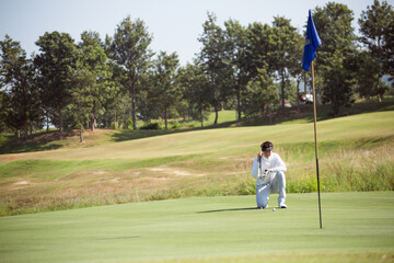 Obraz premium Golfers sit on the green to see the direction of putting golf balls