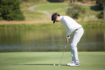 Fototapeta premium Golfers putting golf balls on the green amid the warm sunshine in the morning. Concept of Outdoor activities and Outdoor sports, Concept of Golfer and Lifestyle..