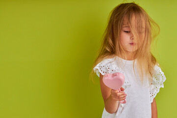 Fototapeta na wymiar shaggy child girl is going to comb hair after waking up, looks away isolated over green background