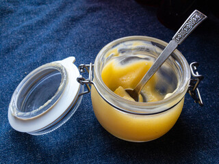 Lemon curd in the glass jar with spoon  on the dark blue background