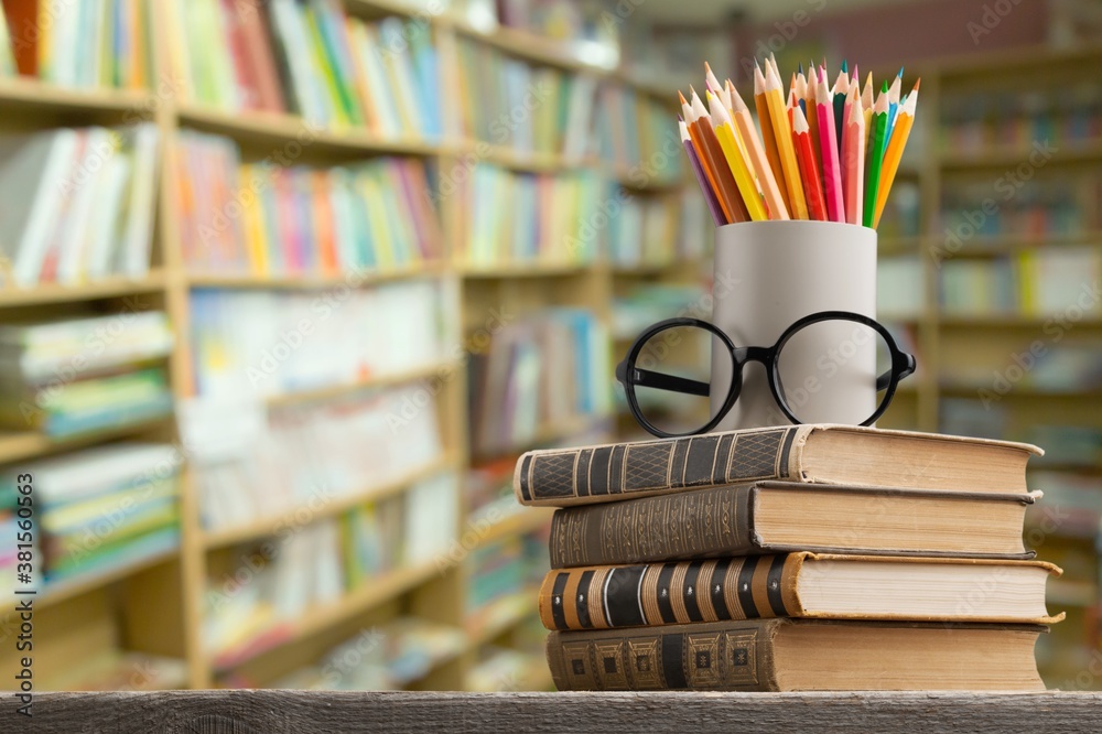 Wall mural Stack of vintage books and colorful pencils on the desk