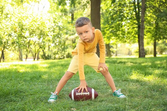 Little boy playing American football outdoors