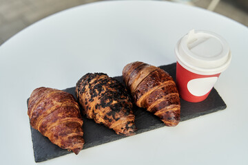 Red cup with coffee and a croissant on a table in a cafe. Morning breakfast. High-quality photo