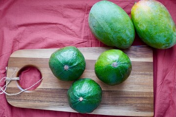 Green avocado and mango on a wooden chopping board against a green background. Healthy food. Style of life. Meals for vegans. Vegetable table