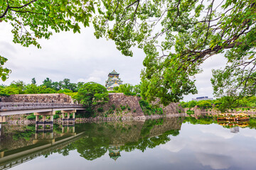 Fototapeta na wymiar Main Building of Osaka Castle Reflection in Moat around Osaka Castle Park in Green Summer Season, Osaka, Japan