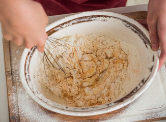 child beating egg and flour for making dough with beater, cook