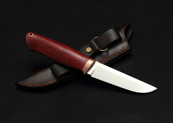 Knife with wooden handle and sheath on black background