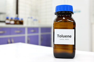 Selective focus of toluene liquid chemical compound in dark glass bottle inside a chemistry laboratory with copy space. Aromatic hydrocarbon used in petrochemical industry.