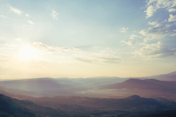 Early morning in the mountains. Morning sun and haze in the valley against the background of mountains. Mountain summer landscape