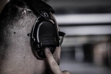 The shooter turns on the headphones in the shooting range before shooting, hearing protection during the shooting, using active headphones, the big plan, soft focus
