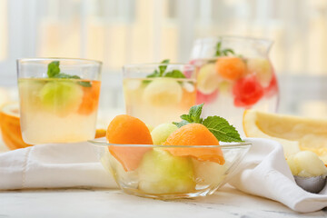 Tasty melon balls with cold cocktail on table