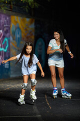 young mother and her little daughter rollerskating in the evening. family have fun