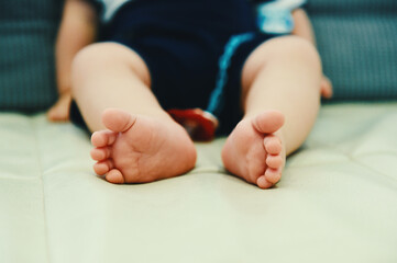 Baby Boy Sitting on a Sofa Showing his Feet.