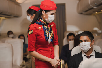 female asian crew serviced on flight, Airline passengers wear protective masks, after the virus crisis people travel but still protect themselves by wearing masks.