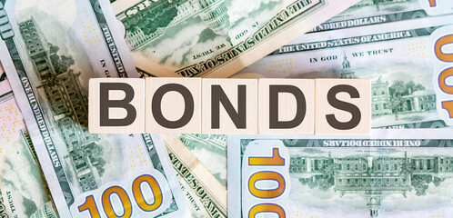 Concept words BONDS on wooden blocks on a beautiful background from dollar bills.
