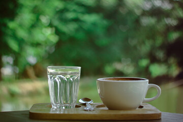 cup of coffee with glass of water on green heart blur background