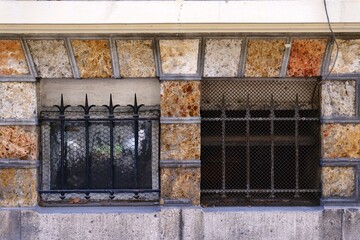 Two windows surrounded by mesh and trident also fenced by square brick wall