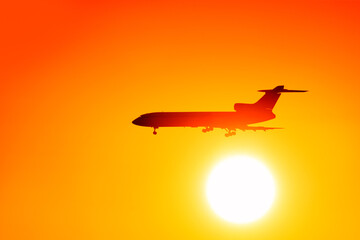 Naklejka na ściany i meble jet airplane flying against sunset sky background. Passenger plane landing with setting sun. Silhouette of modern aircraft at sunrise. Side view of airliner. Natural color of sunset sky Aviation theme