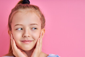 sly little girl is looking away, she conceived something, isolated on pink background